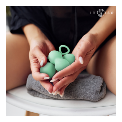 Pessoa segurando bolas verdes de silicone com anel sobre toalha cinzenta