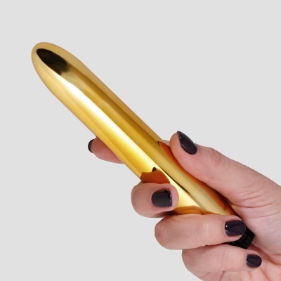 Mão a segurar objeto metálico dourado
