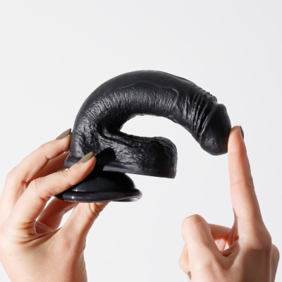 Objeto preto em forma de espiral com textura enrugada, segurado por mãos contra fundo branco.
