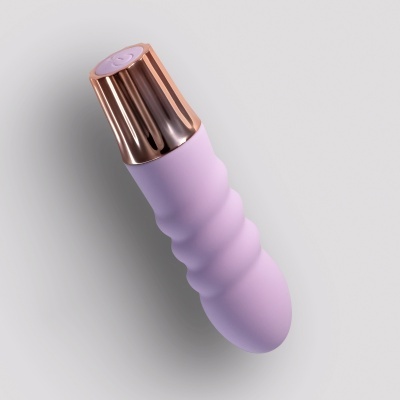 Vibrador lilás com acabamento dourado em fundo cinza claro