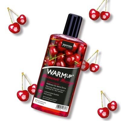 Frasco de óleo para massagem com líquido vermelho e cerejas ao redor