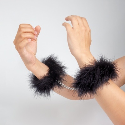 Algemas de pelúcia pretas com corrente metálica prateada nos punhos.