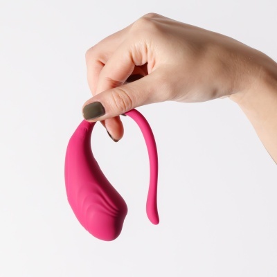 Mão segurando objeto rosa de silicone com textura e formato curvo