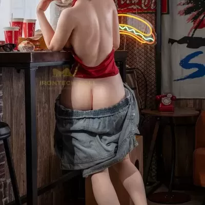 Figura feminina loira com vestido vermelho sem costas encostada num balcão de madeira com luzes neón ao fundo
