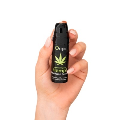 Frasco preto de gel íntimo Orgie Hemp com doseador, segurado numa mão com unhas pintadas de nude.