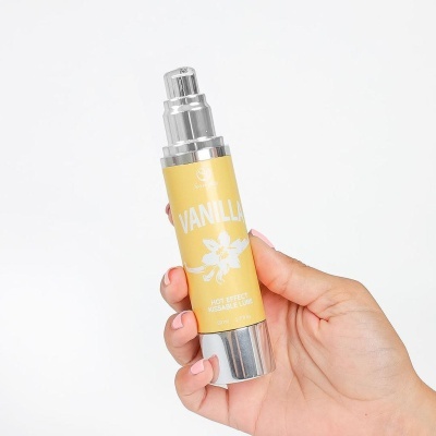 Frasco de lubrificante vanilla com doseador prateado nas mãos
