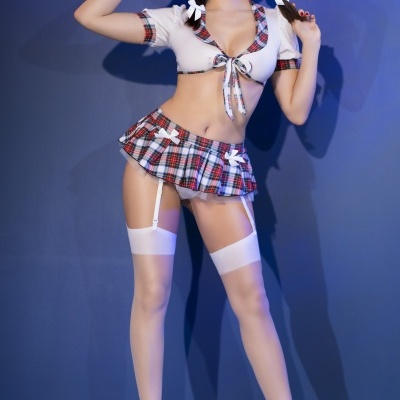 Conjunto de lingerie xadrez vermelho e branco com meias e salto alto branco por modelo em fundo azul.