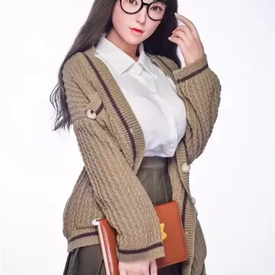 Boneca realista vestindo camisa branca, cardigan castanho e saia verde, com óculos e segurando um livro castanho