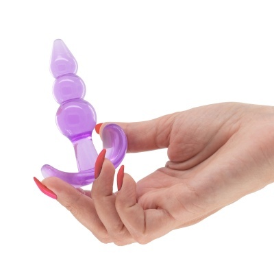 Objeto roxo translúcido com esferas segurado por mão com unhas vermelhas