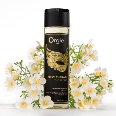 Frasco de óleo para massagem Orgie rodeado por flores brancas
