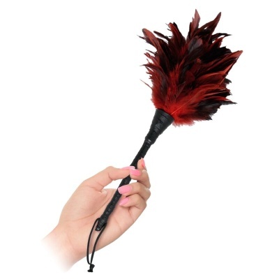 Pena vermelha e preta com cabo preto segurada por mão com unhas cor-de-rosa