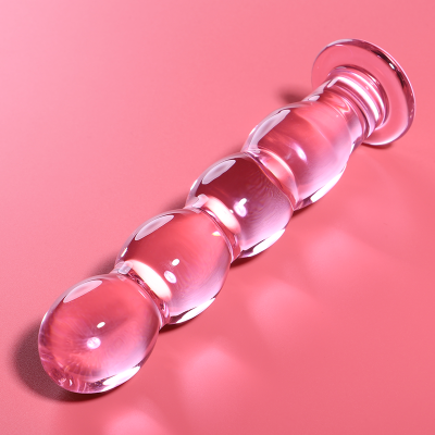 Objeto de vidro transparente com esferas em cima de superfície rosa