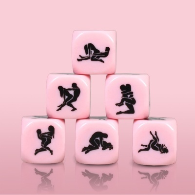 Dados cor-de-rosa com desenhos negros de posições sexuais empilhados em pirâmide