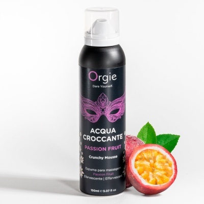 Frasco de espuma para massagem Orgie Acqua Croccante Passion Fruit ao lado de maracujás.