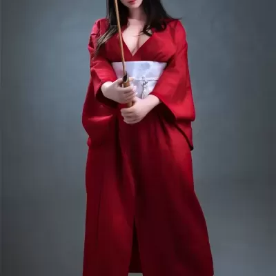 Boneca realista com quimono vermelho e faixa branca segurando espada