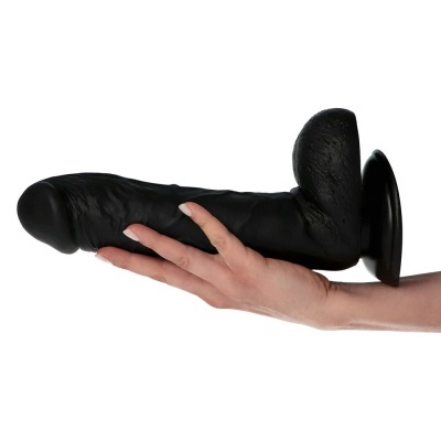 Dildo preto em silicone com ventosa, segurado por uma mão.