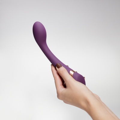 Vibrador roxo em silicone seguro por uma mão