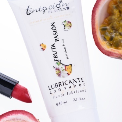 Tubo branco de lubrificante sabor fruta paixão com batom vermelho e fruta cortada ao lado
