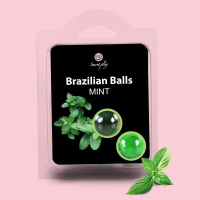 Embalagem transparente com duas bolas verdes e folhas de menta sobre fundo rosa