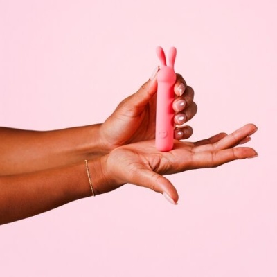 Mãos seguram vibrador cor-de-rosa com design de duas pontas