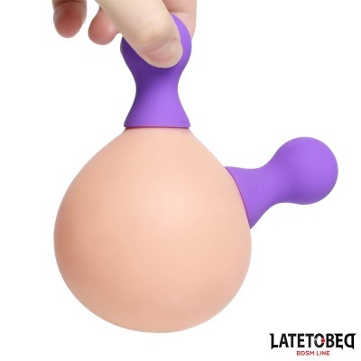 Dispositivo de silicone cor de pele com alças roxas segurado por mão sobre fundo branco
