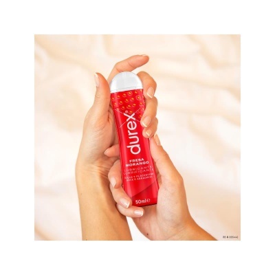Frasco vermelho de lubrificante Durex sabor fresa e morango nas mãos