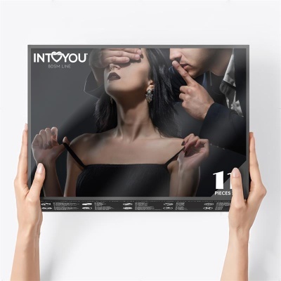 Embalagem de conjunto BDSM INT*YOU com 11 peças, mulher de vestido preto e homem a tapar olhos e fazer sinal de silêncio
