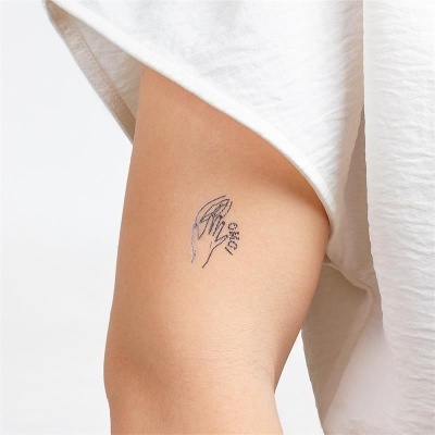 Tatuagem temporária de mão segurando uma folha no braço