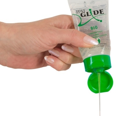 Mão feminina a segurar tubo transparente de lubrificante com tampa verde aberto