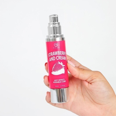 Frasco de lubrificante beijável efeito quente morango e creme segurado por uma mão