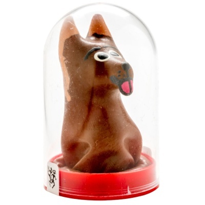 Figura de cão castanha com olhos grandes e língua rosa dentro de cúpula de plástico