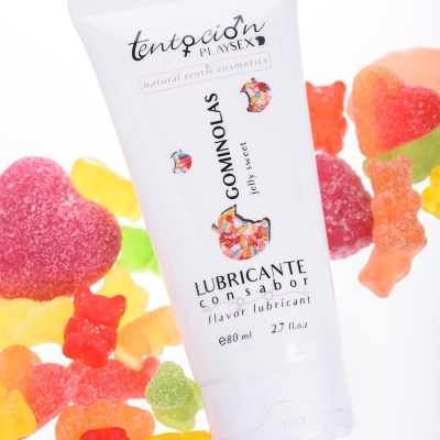 Frasco branco de lubrificante saborizado cercado por gomas de gelatina coloridas e açucaradas