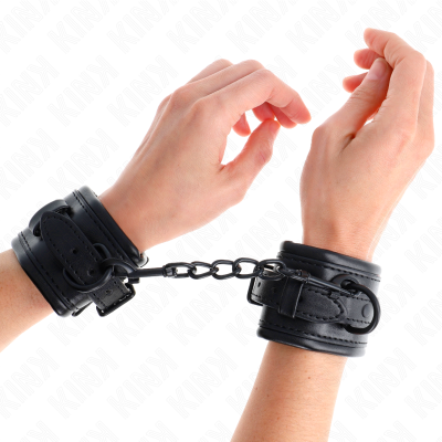 Algemas de couro preto com corrente metálica entre os pulsos
