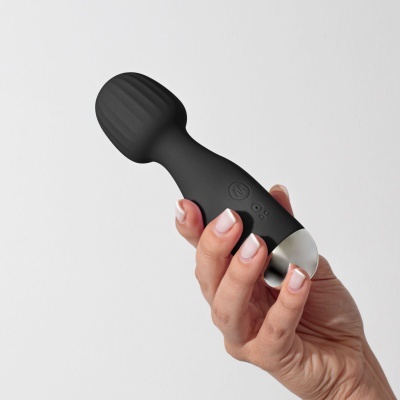 Dispositivo preto com cabeça oval e botões segurado por mãos.