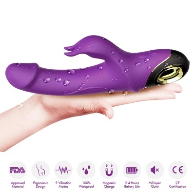 Vibrador roxo anatómico com secção preta e detalhes dourados, gotas de água, sobre mão humana
