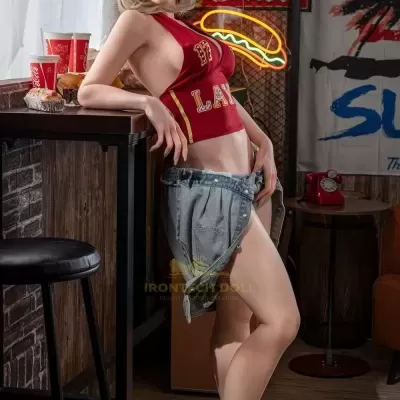 Boneca realista com roupa vermelha e saia jeans ao lado de balcão de madeira e luzes neon CocaCola