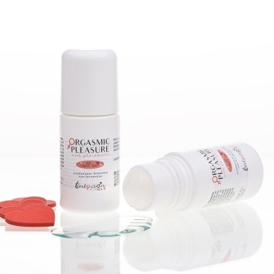 Dois frascos roll-on brancos com rótulo de produto de estímulo feminino e corações vermelhos de madeira.