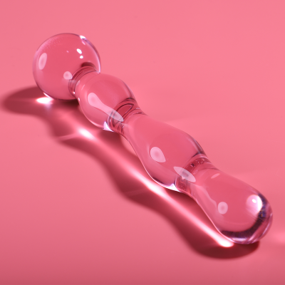 Dildo de vidro transparente sobre superfície rosa