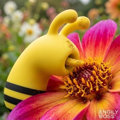 Brinquedo amarelo em forma de abelha sobre flor rosa e amarela num jardim