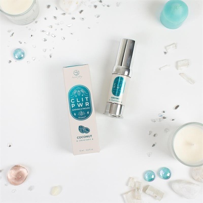 Balm clitoral CLIT PWR sabor coco com embalagem e elementos decorativos sobre superfície branca