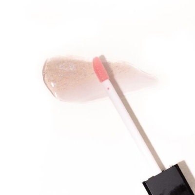 Aplicador de gloss labial com cabo branco e tampa preta sobre mancha translúcida rosada