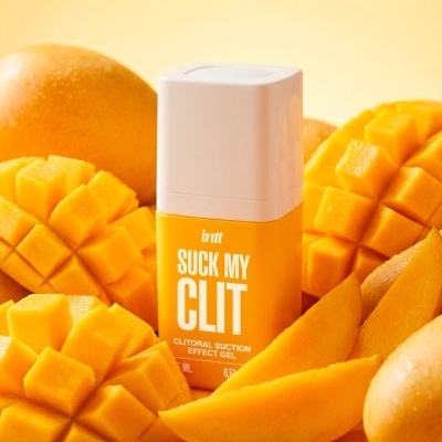 Frasco de gel amarelo e branco com texto SUCK MY CLIT entre mangas frescas cortadas e inteiras