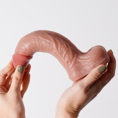 Objeto curvado cor de pele com textura enrugada segurado por mãos