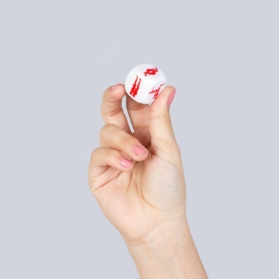 Mão feminina segurando dado branco com desenhos vermelhos