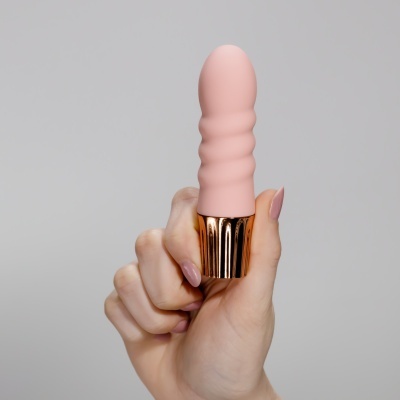 Mão segurando vibrador rosa claro com base metálica dourada