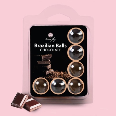 Embalagem com seis bolas de chocolate e duas barras de chocolate ao lado sobre fundo rosa.