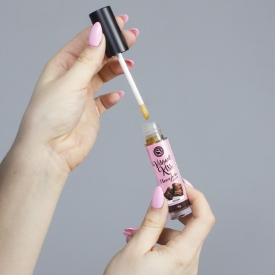 Mãos segurando gloss labial rosa com aplicador e texto Vibrant Kiss