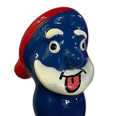 Escultura de cerâmica azul com rosto caricatural e chapéu vermelho