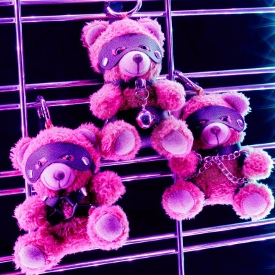Ursinhos de peluche cor-de-rosa com máscara preta pendurados em estrutura metálica prateada