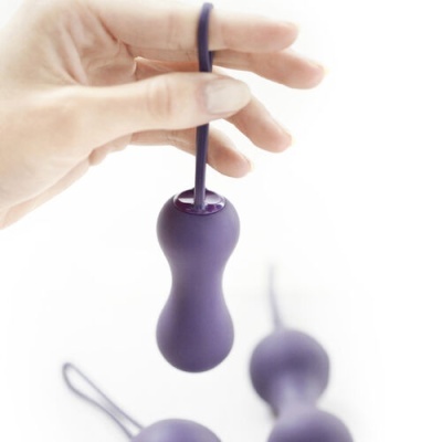 Bola vaginal dupla roxa em silicone com cordão segurada por mão feminina
